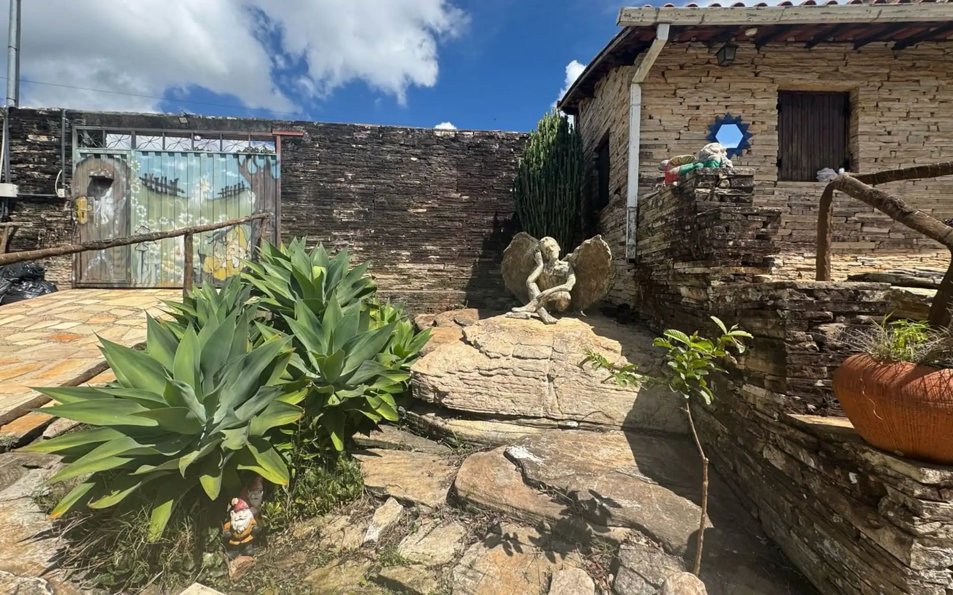 Caminho de pedra da pousada entre agaves, sob céu azul